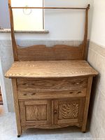 Full front view of oak dry sink in corner, showing overall condition and casters