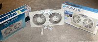 Photo of 3 Bionaire digital window fans, two boxed and one displayed with remote control in front.