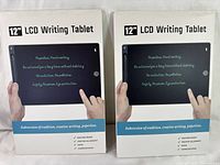 Photo showing two sealed retail boxes of 12 inch LCD Writing Tablets with product image and features.