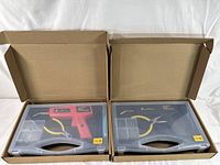Two open boxes showing the plastic carrying cases with hot stapler plastic welding torches, needle-nose pliers, and metal staples inside.