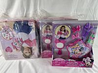 Photo of seven sealed Disney Junior Minnie Mouse fashion accessory sets, showing the front and back packaging with a young girl model.