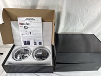 Open black box showing two round RGB LED headlights in foam with connection instruction sheet inside the box.