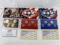 Photo showing three United States Mint proof coin sets including 50 State Quarters sets in red and blue packaging, and a 2007 Presidential $1 Coin set with certificate.