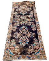 Full view of antique Persian runner rug showing dark central medallion floral design in shades of black, cream, blue, and green with beige border.