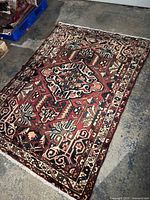 Full view of the rectangular Bakhtiari rug on a concrete floor, displaying its intricate geometric pattern and natural color palette.
