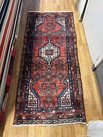 Full view of rectangular runner rug laid out on wooden flooring showing overall pattern and design colors.