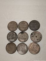 Nine US wheat pennies shown all facing reverse with 'ONE CENT' and 'UNITED STATES OF AMERICA' inscriptions visible; various wear and discolorations evident.