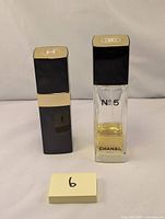 Two Chanel No. 5 perfume bottles with caps, one partially full, one empty, displayed on plain background.