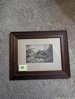 Framed print of a bird in flight, shown fully framed with dark wooden frame on carpeted surface.