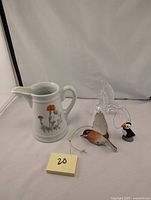 Photo showing 5-inch ceramic floral pitcher with three bird ornaments placed around it.