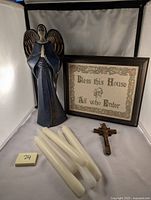 Full view of metal angel figure, framed Petite Pointe embroidery sign, vintage wooden Jesus cross, and white candles on white background.