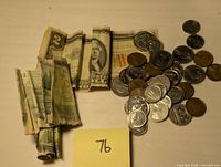 Wide view of lots showing rolled and loose US and Canadian coins with multiple folded bills including the 1953 red seal $2 note and other worn bills.
