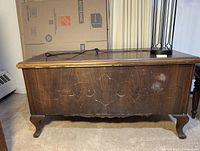 Oak chest front showing carved floral and scroll detail with visible staining and missing keyhole insert.