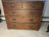 Full front view of oak dresser showing five drawers with ornate brass handles and keyholes.
