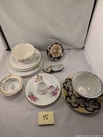 Overall lot view showing array of porcelain and jasperware items including teacups, plates, trinket bowl, shoe figurine, and mini stand