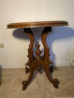 Full view of the Victorian style oval walnut side table showing the oval top and ornate carved base with three curved legs.