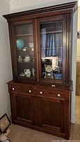 Front view of the solid dark wood vintage hutch showing glass doors and drawers.