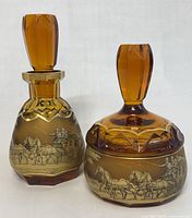 Front view of amber glass decanter with stopper alongside lidded bowl