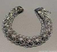 Two braided silver bracelets arranged to show overall design and length on flat surface.