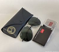 Ray-Ban sunglasses with black case and cleaning cloth with booklet laid out on a surface