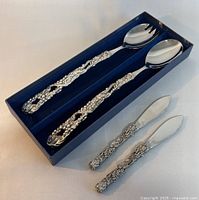 Serving cutlery set in original box, showing two serving spoons with detailed grapevine motif handles in pewter