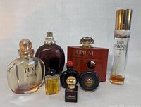 Photo of seven different perfume bottles showing identifying labels including Yves Saint Laurent Opium, Christian Dior Dune and Poison, Elizabeth Taylor White Diamonds, Ralph Lauren Lauren, and two other small bottles.