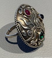 Side angle showing the ring's design, silver band, and gemstones with shadow cast on surface
