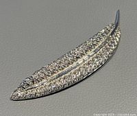 Close-up photo of the front of the silver-tone leaf brooch showing clear crystals and detailed leaf veins.