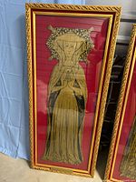 Full view of framed brass rubbing showing a medieval female figure in detailed attire, mounted on red velvet with gold frame.