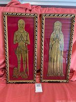 Pair of framed medieval brass rubbings in gold-toned brass on red velvet and black mat, ornate carved gold frames