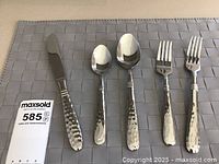 Full set of five flatware pieces showing knife, two spoons, and two forks with hammered handles and polished blades/tines.