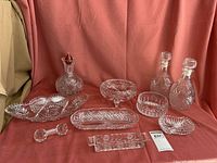 Wide view of all cut crystal items including two decanters, several bowls, divided tray, and smaller dishes.