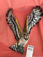 Resin eagle sculpture with fish, detailed feathers, and painted realistic colors on a red fabric background.