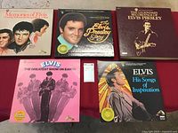 Five Elvis Presley vinyl albums laid out on a surface, showing album covers featuring Elvis in different artistic and photographic representations.