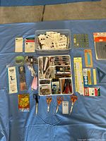Overview of all sewing notions including boxes of buttons, scissors laid out, measuring tools and small accessory items.