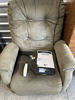 Front view of sage lift recliner with remote, power adapter and manual on seat
