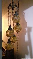 Overall view of five amber glass globes suspended in cascade from ceiling hook