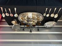 Full view of plated silver items including goblets, spoons, footed bowl, candleabra, and serving dish