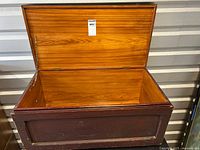 Open view of wooden blanket chest showing cedar lining inside and brass hardware on edges.