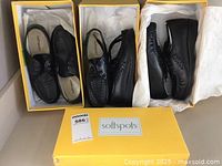 Three pairs of black ladies shoes in yellow Softspots boxes viewed from above showing the design and brand name inside the shoes.