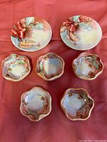 Five small hand-painted salt bowls with scalloped edges and matching acorn and leaf design on red fabric