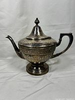Front view of Apollo Etchardt antique hammered metal teapot showing overall shape, spout, handle and lid.