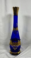 Front view of entire vintage cobalt blue glass decanter showing tall neck, wide base, and gold decorative bands.