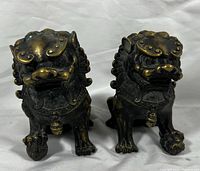Front view of the pair of bronze Chinese Foo Dog statues showing fine details and patina.