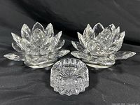 Photo showing two Shannon Crystal lotus flower shaped candle holders and one small open salt cellar dish arranged in a triangle on black background.
