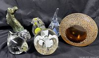 Full view of five glass paperweights including bird, horse head, flower, geode votive, and bronze horse head on glass base