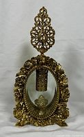 Front view of the vintage gold plated perfume bottle with clear beveled glass and ornate filigree stopper.