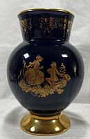 Full front view of oval cobalt blue vase with gold footed base and gold courting couple scene on front.