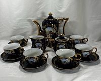 Complete cobalt blue and gold Limoges porcelain tea set arranged with teapot, creamer, sugar bowl, 6 cups and saucers showing overall set appearance.