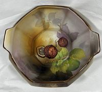 Top view of triangular-shaped hand-painted bowl showing detailed raised chestnuts and foliage pattern in brown, green, and purple.